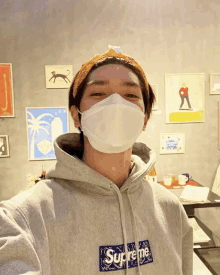 a man wearing a face mask and a supreme sweatshirt