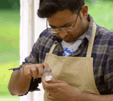 a man wearing glasses and an apron is holding a jar with a label that says ' a ' on it