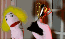 a hand holding a trophy with a puppet in the background