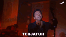 a man is singing into a microphone and the word terjauh is on the bottom