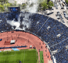 an aerial view of a soccer stadium with smoke coming out of it