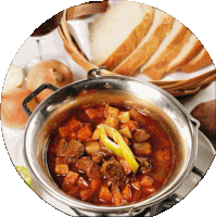 a pot of stew sits on a table next to a basket of bread