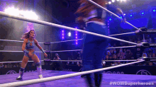 a woman in a wrestling ring with #wowsuperheroes written on the bottom