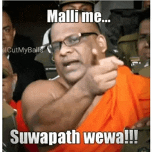 a man wearing glasses and an orange shirt is pointing at the camera and says malli me suwapath wema !!!