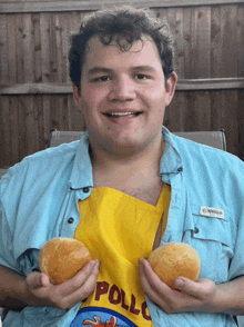 a man wearing a magellan shirt is holding two rolls of bread