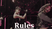 a woman in a black dress is dancing on a stage in front of a neon sign that says rules .