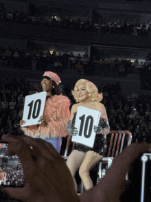 two drag queens are holding up signs that say 10