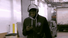 a man wearing headphones is looking at his phone while walking