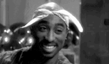 a black and white photo of tupac shakur wearing a bandana and a hat .