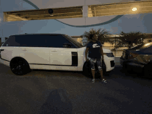 a woman wearing a nike shirt is standing next to a white suv