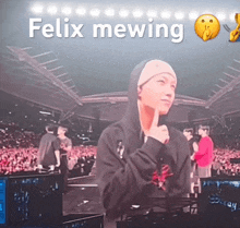 a man in a hooded sweatshirt stands in front of a crowd with the words felix mewing above him