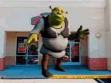 shrek from the movie shrek is standing in front of a building .