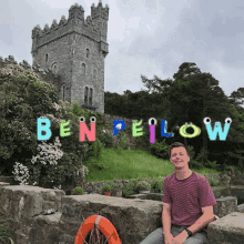 a man sits on a stone wall in front of a castle with the name ben pellow written on the letters