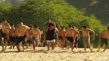 a group of men are walking on a sandy beach with the words never give up wins written on the bottom right