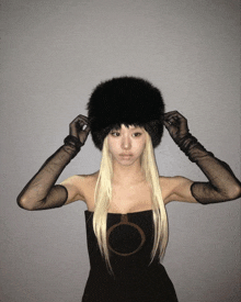 a woman with blonde hair wearing a fur hat and gloves