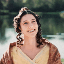 a woman with curly hair is smiling and wearing a yellow dress