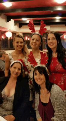 a group of women are posing for a picture with one wearing a reindeer headband