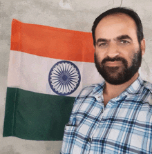 a man with a beard stands in front of a flag of india