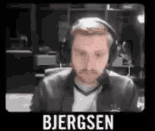 a man wearing headphones is sitting in front of a screen with the name bjergsen on it .