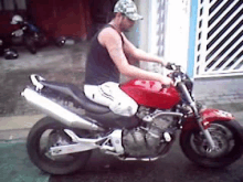 a man is sitting on a red motorcycle in front of a garage .