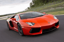 a red lamborghini is driving down a road