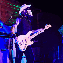 a man in a cowboy hat is playing a guitar in front of a sign that says ' art ' on it