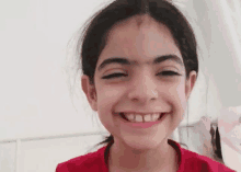 a young girl wearing a red shirt is smiling