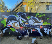 a chair sits in front of a wall with graffiti on it and a staircase in the background