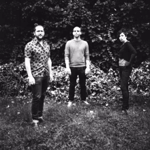 a group of three people standing in a grassy field