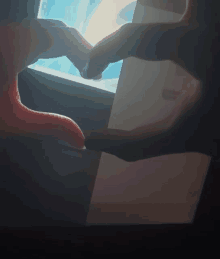 a person making a heart shape with their hands in front of a computer screen