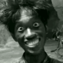 a black and white photo of a man with big eyes smiling and making a funny face .