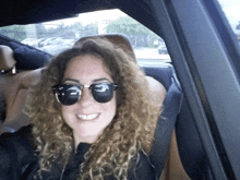 a woman wearing sunglasses is smiling while sitting in the back seat of a car