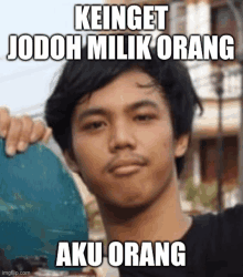 a man is holding a skateboard with a caption that says keinget jodoh milik orang aku orang .