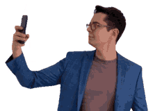 a man in a blue suit and glasses is taking a selfie with his phone