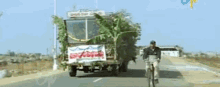 a man is riding a bike down a road next to a truck with a sign on it that says ' aa '