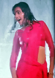 a woman in a red crop top is dancing in the rain .