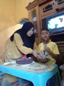 a woman in a yellow shirt is cutting a cake with candles on it