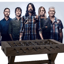 a group of men standing in front of a foosball table that says ' foo fighters ' on it