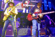 a man and a boy are playing guitars on a stage in front of a large screen .