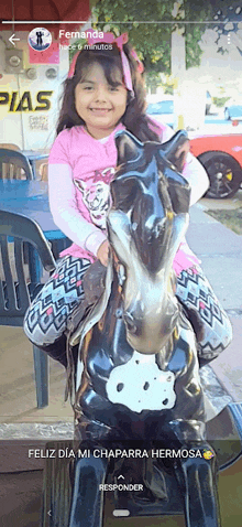 a little girl is sitting on a statue of a horse and the caption says fernanda