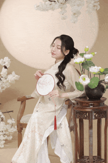 a woman sitting in a chair with a fan in her hand