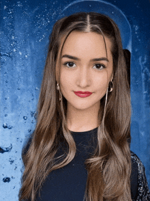 a girl with long brown hair and red lips is standing in front of a blue background