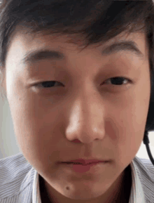 a close up of a young man 's face with a striped shirt on