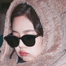 a close up of a woman wearing sunglasses and a fur coat .