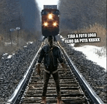 a man is standing on train tracks with a train coming down the tracks .