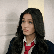 a girl wearing a red tie and a suit looks to the side