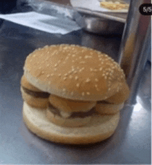 a hamburger on a bun with sesame seeds on a table