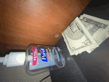 a bottle of purell hand sanitizer sits next to a stack of money