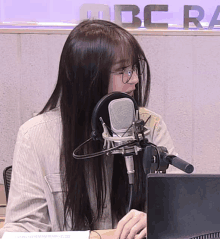 a woman with long hair is sitting in front of a microphone in front of a sign that says bbc radio