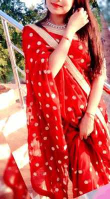 a woman is wearing a red saree with white polka dots and a necklace .